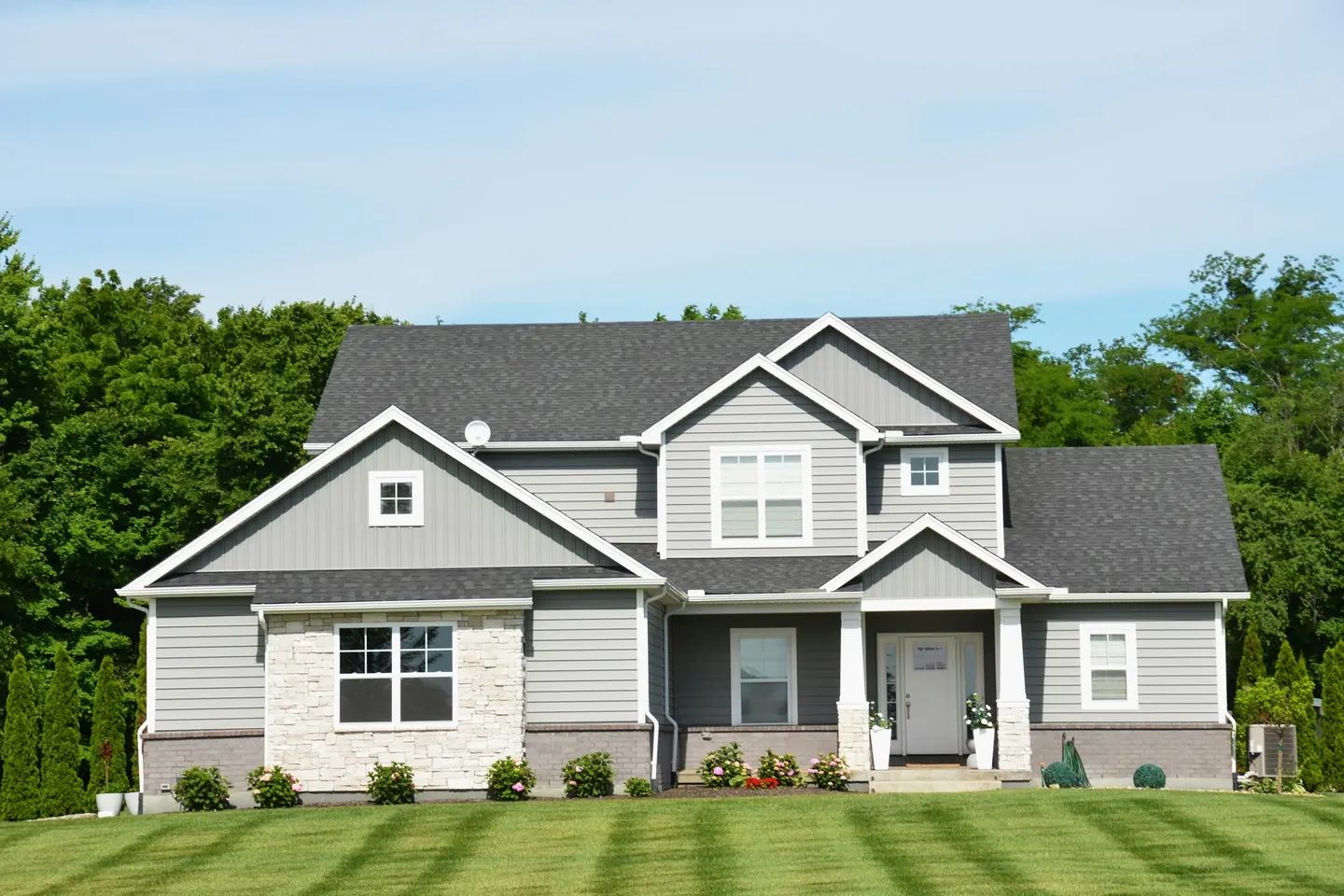 A suburban lawn cut in clean stripes running up to the house